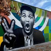 black and white mural of Muhammad Ali with a colorful background on a building in Louisville